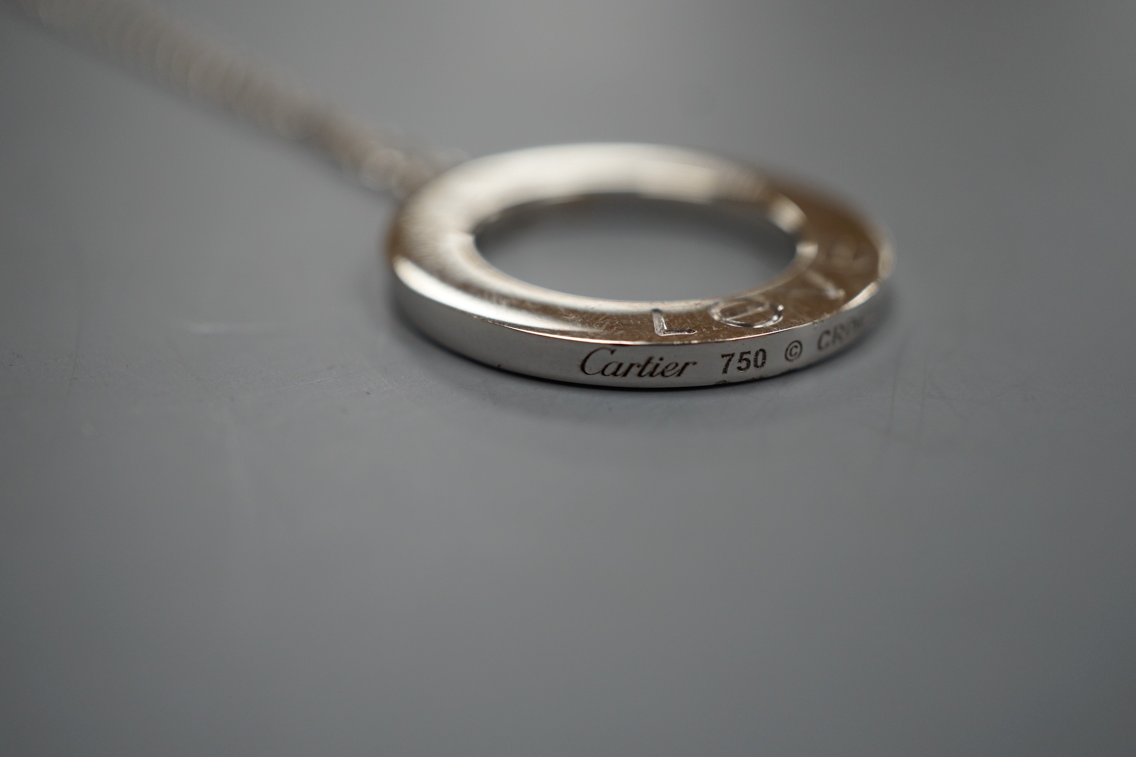 A modern Italian Cartier 750 white metal 'Love' circular pendant, 24mm, numbered CRD612779, on a 750 white metal fine link chain, 46cm, 10.8 grams.